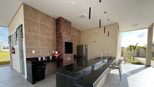 A modern kitchen with a central island, a brick oven, pendant lights, and a view of the outdoors. - Caminho das Bromélias Lodging – Caruaru (Caruaru)