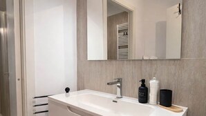 Een badkamer met een witte wastafel, een grote spiegel, een handdoekhouder en een toilet.