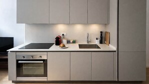Een moderne keuken met een inbouwoven, een kookplaat, een spoelbak en een koelkast.