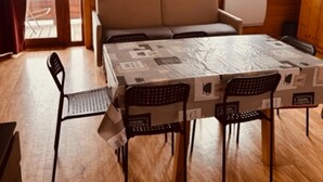 Une pièce comprenant un canapé, une table à manger avec des chaises, un radiateur et une fenêtre avec des rideaux.