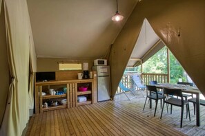 Ein gemütliches Blockhaus mit Küchenzeile, einer Essecke mit Tisch und Stühlen sowie einer Holzterrasse.