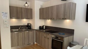 A compact kitchen with wooden cabinets, a built-in oven, and a dining area with a white table. - 200m from ski slopes, 1st floor, terrace, tv, ski locker, 38m², Saint Gervais (Saint-Gervais-les-Bains)