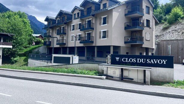 A multi-story hotel with balconies, a sign reading 'CLOS DU SAVOY,' and a mountainous backdrop. - 200m from ski slopes, 1st floor, terrace, tv, ski locker, 38m², Saint Gervais (Saint-Gervais-les-Bains)