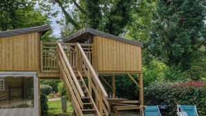 Una cabaña de madera con un balcón y una escalera que lleva a una terraza.