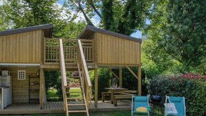 Una cabaña de madera con un balcón, una escalera, una mesa de picnic y dos sillas.
