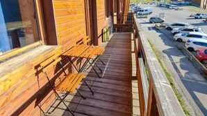 Un edificio de madera con un balcón que da a un estacionamiento y un paisaje montañoso.