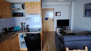 Un espacio habitable compacto con kitchenette, comedor y zona de estar.