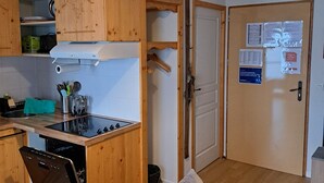 Una cocina compacta con armarios de madera, estufa integrada y una lámpara colgante.