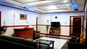 Eine Hotellobby mit Rezeption, Sitzgelegenheiten, einem Fernseher und einer Tür mit der Nummer 5.