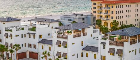 A coastal hotel with multiple white buildings, balconies, and a view of the sea.