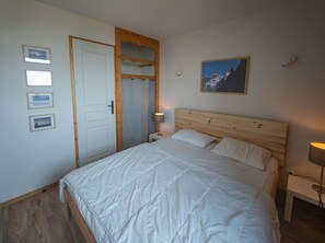 Une chambre à coucher avec un lit, une tête de lit en bois, une table de chevet avec une lampe et des tableaux encadrés accrochés au mur.