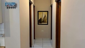 Un couloir doté d’un sol carrelé, d’une œuvre d’art encadrée au mur et d’un porte-manteau muni de crochets.