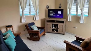 Un salon avec un téléviseur, des meubles en bois et des rideaux.