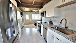 Una cocina moderna con armarios blancos, electrodomésticos de acero inoxidable y una encimera de granito.