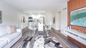 Una sala de estar moderna con un sofá, una mesa de comedor y una cocina al fondo.