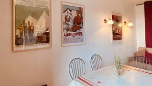A dining area with a table set for four, metal chairs, and wall-mounted light fixtures. - Apartment 'Les Edelweiss 201' Large Terrace with Mountain and Valley Views (Chamrousse)
