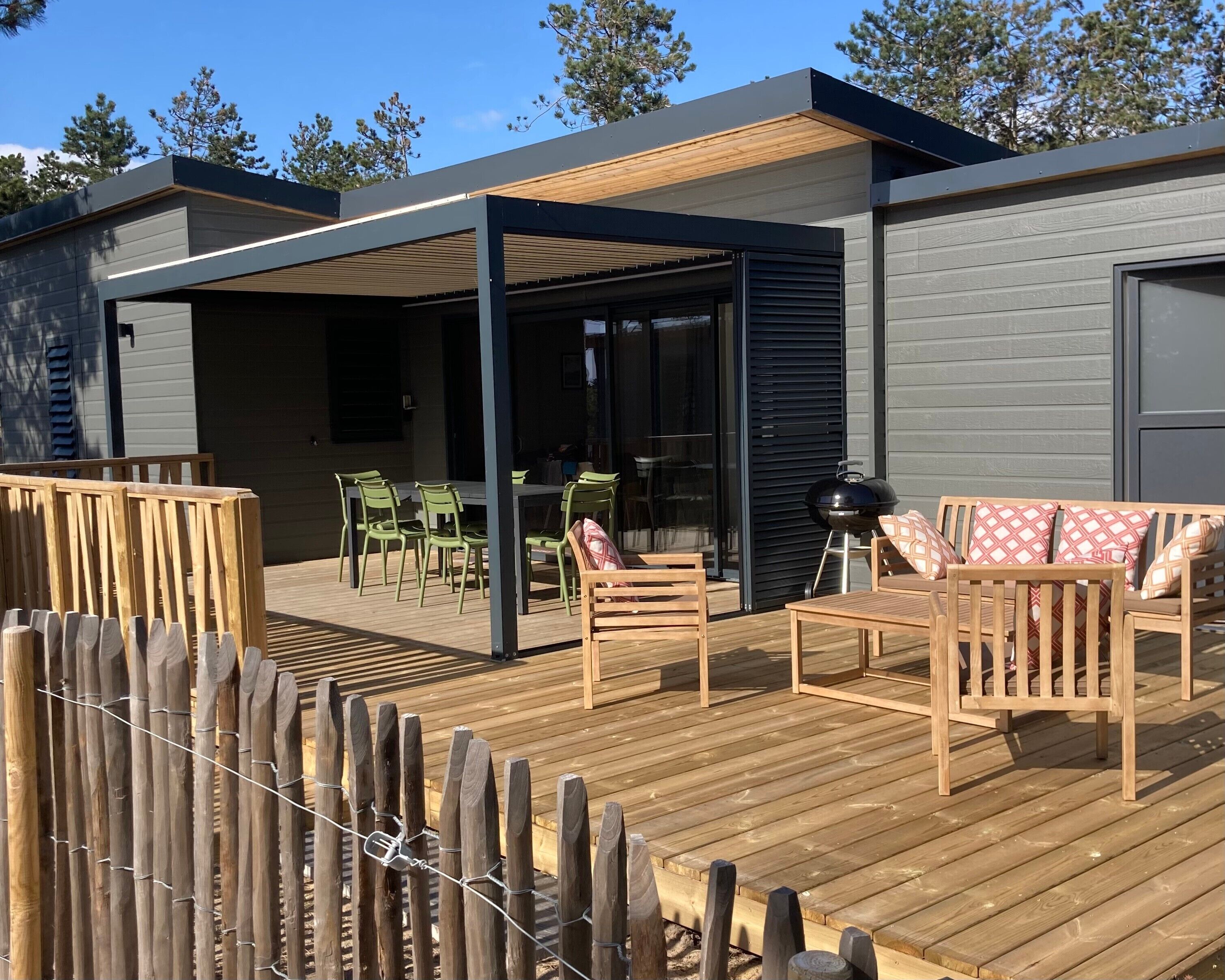A covered outdoor patio with wooden furniture, a grill, and a dining area.