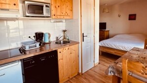 A compact kitchen with wooden cabinets, a microwave, and a dishwasher. - Studio 'Le Bouquetin 304' for 2 – Les Balcons du Recoin, Chamrousse 1650 (Chamrousse)