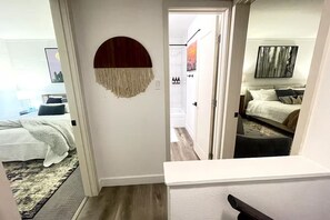 A bedroom with a bed, a wall-mounted circular decor, and a door leading to another room. - Southwest Meets Boho Old Town Scottsdale Townhome (Scottsdale)