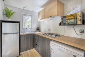 Eine kleine Küche mit Kühlschrank, Herd, Mikrowelle und Geschirrspüler.