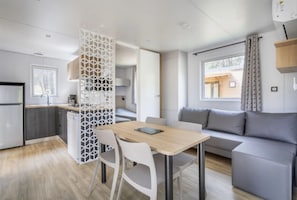Ein kompakter Wohnraum mit einer Küchenzeile, einem Essbereich und einer Sitzecke inklusive Sofa und Tisch.