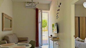 A room with a dining table, chairs, a sofa, a TV, and a bed. - Encanto Alcázar - Ole Solutions (Jerez de la Frontera)
