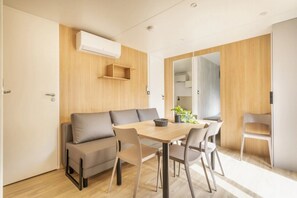 Ein stilvolles Zimmer mit Sofa, Esstisch, Stühlen und einer Holzwandverkleidung.