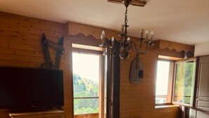 A wooden interior with a large table, a bench, a television, and a chandelier. - Duplex Apartment 'Les 7 Marmottes', 306, Mountain View and Balcony (Chamrousse)