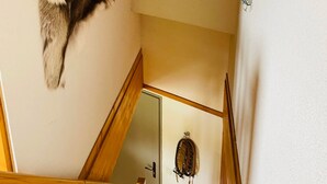 A room with a wooden staircase, a fur rug on the wall, and a door with a circular decoration. - Duplex Apartment 'Les 7 Marmottes', 306, Mountain View and Balcony (Chamrousse)