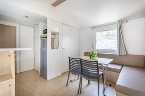 Ein gemütlicher Raum mit Esstisch, Stühlen, einer Couch, einem Fenster mit Vorhängen und einem Einbauschrank.