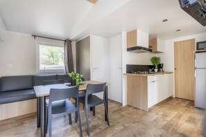 Eine kompakte Küche mit Essbereich, fest eingebautem Herd und einem Fenster mit Vorhängen.