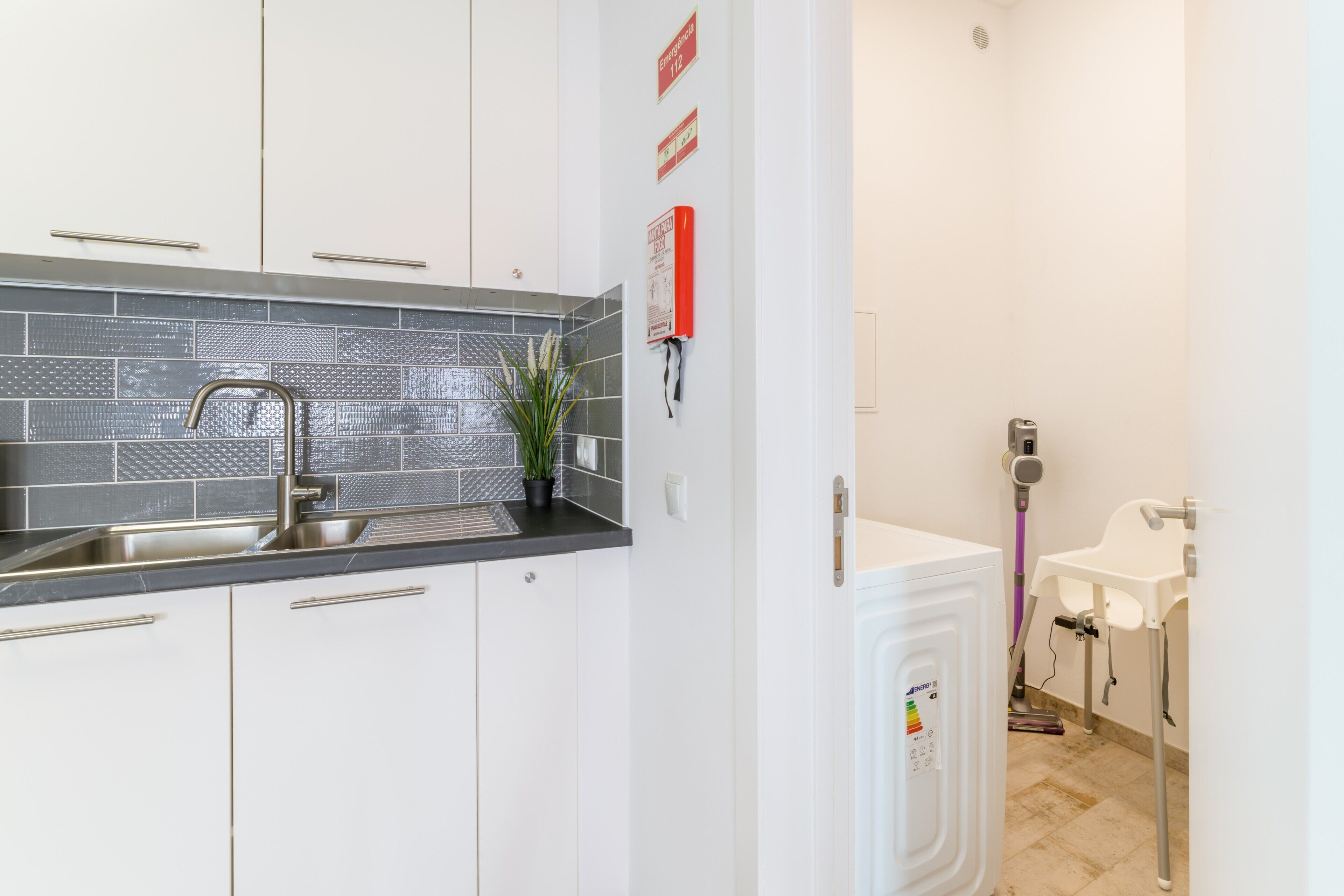 A modern kitchen with a sink, cabinets, and a tiled backsplash.