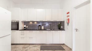 A modern kitchen with white cabinets, a black countertop, a built-in oven, and a tiled backsplash.
