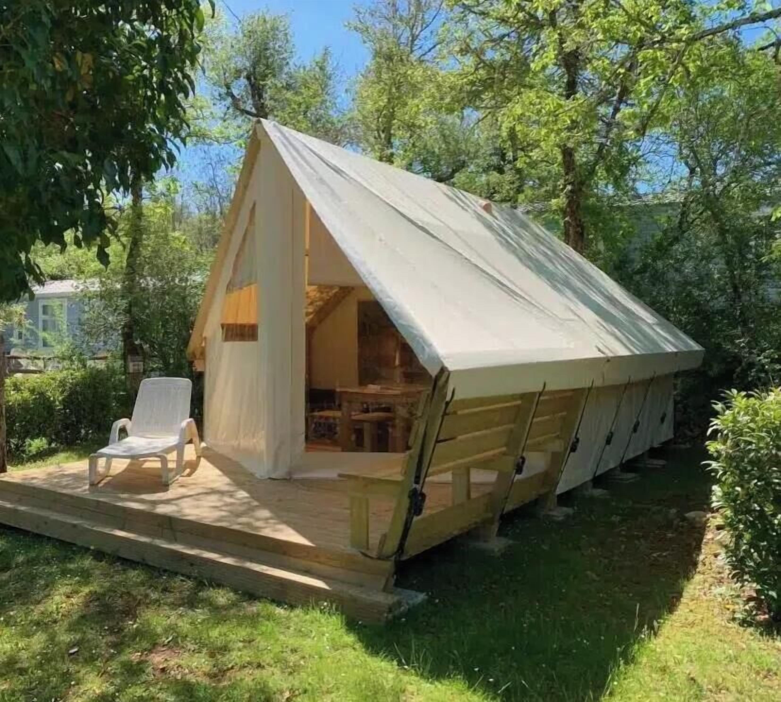 En liten, enplansstuga med ett sluttande tak, en veranda med en stol och en synlig interiör med ett bord och stolar.