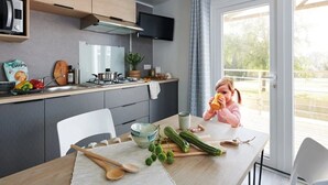 Een moderne keuken met een eethoek, een televisie boven de toonbank en uitzicht op het omliggende landschap.