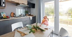 Eine moderne Küche mit Essbereich, einem über der Arbeitsfläche montierten Fernseher und Blick ins Freie.