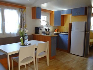 Eine kleine Küche mit Esstisch, Stühlen, Kühlschrank und Schränken.