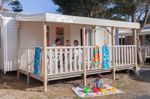 Ein Bungalow mit Veranda, einer kleinen Terrasse und einem überdachten Außenbereich.