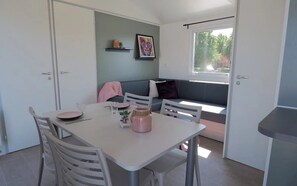 Ein Essbereich mit Tisch, Stühlen, einer Couch und einem Fenster mit Blick auf Bäume.