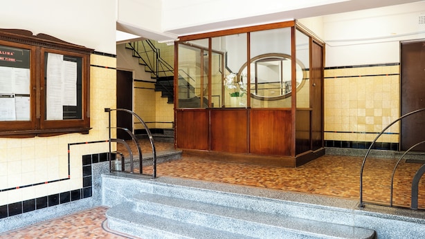 Una hall con una scala, un armadio in legno e un pavimento piastrellato.