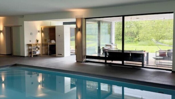Piscina interior moderna com vista clara para o exterior.