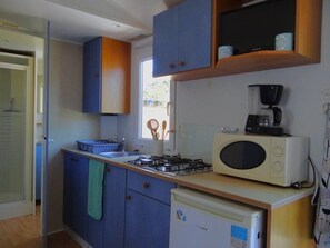 Eine kompakte Küche mit Mikrowelle, Kaffeemaschine und kleinem Kühlschrank.