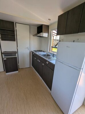 A compact kitchen with a gas stove, sink, and a white refrigerator. - Camping 2 étoiles - ccbg00a (Sémeries)