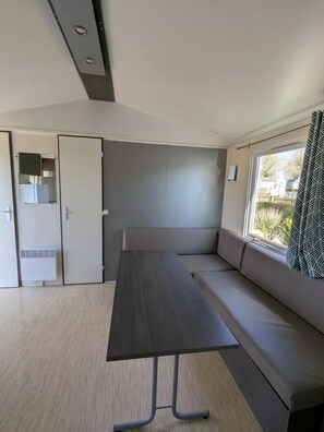 Une pièce moderne avec une table en bois foncé, un canapé gris et une fenêtre ornée de rideaux à motifs.
