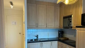 A compact kitchen with wooden cabinets, a microwave, and a coffee maker. - Stunning Seaview Apartment With Balcony (Blankenberge)