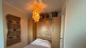 A bedroom with a bed, a bedside table, a hanging light fixture, and built-in cabinets. - Stunning Seaview Apartment With Balcony (Blankenberge)