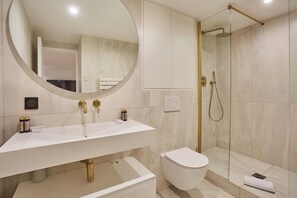 Une salle de bain moderne avec un lavabo blanc, des toilettes et une douche à parois de verre.