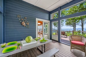 A deck with a table set for dining, a wicker chair, and a view of the outdoors. - Eagleview Basecamp | Panoramic Pisgah Forest Views (Pisgah Forest)