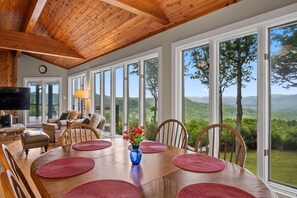 A dining area with a wooden table, red placemats, and a vase of flowers. - Eagleview Basecamp | Panoramic Pisgah Forest Views (Pisgah Forest)