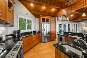 A modern kitchen with wooden cabinets, stainless steel appliances, and a black granite countertop. - Eagleview Basecamp | Panoramic Pisgah Forest Views (Pisgah Forest)